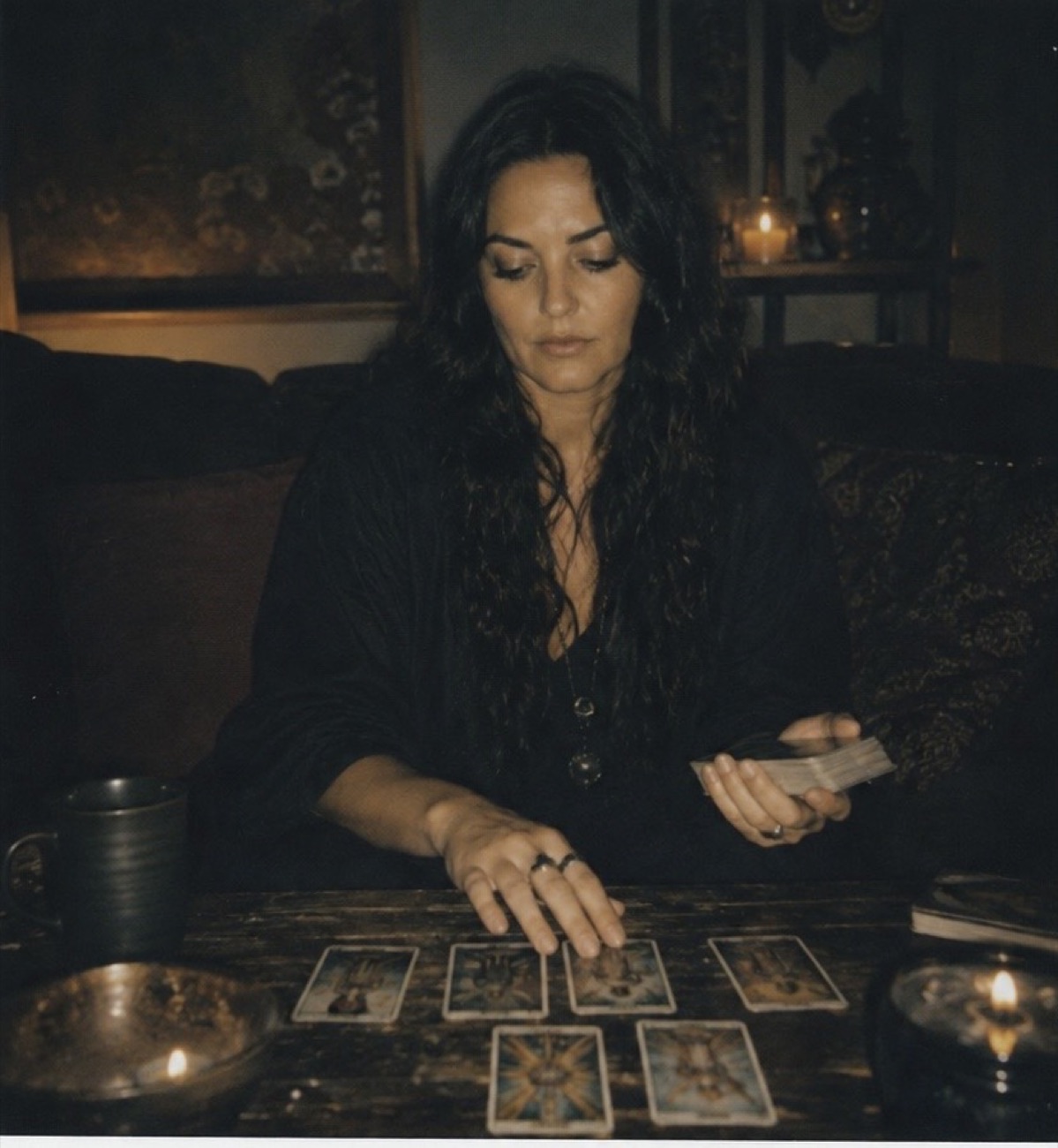 Chaya sitting at her table with The Chariot, The Sun, and The Moon tarot cards